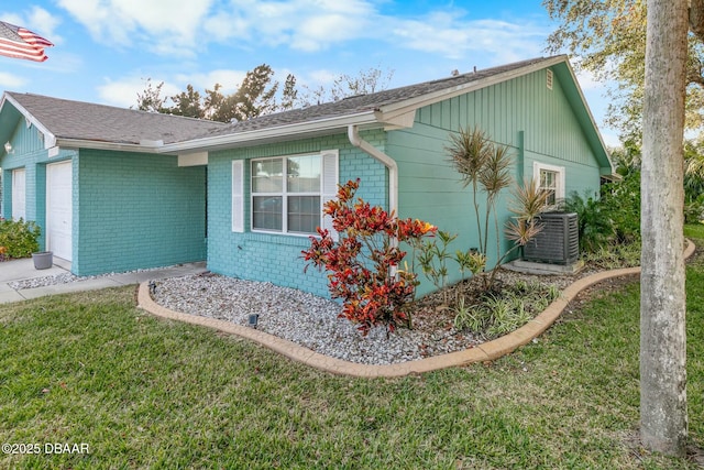 view of side of property featuring a garage, central air condition unit, and a yard