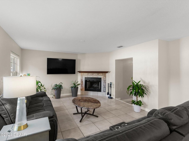 living room featuring visible vents, baseboards, light tile patterned flooring, and a tile fireplace