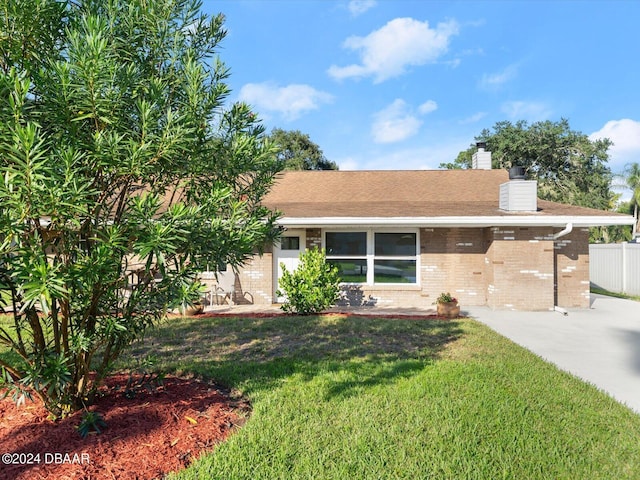 single story home featuring brick siding, a chimney, a front yard, and fence