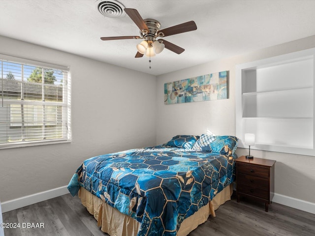 bedroom featuring ceiling fan, visible vents, baseboards, and wood finished floors