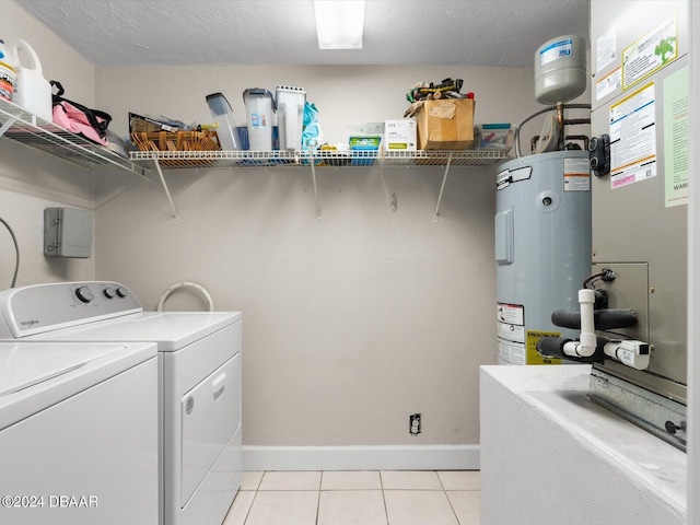 laundry area with electric water heater, washing machine and dryer, light tile patterned floors, baseboards, and laundry area