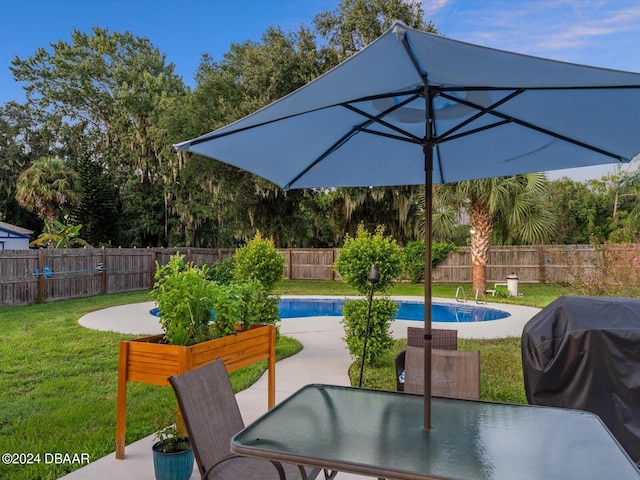 view of patio featuring grilling area, a fenced in pool, outdoor dining space, and a fenced backyard