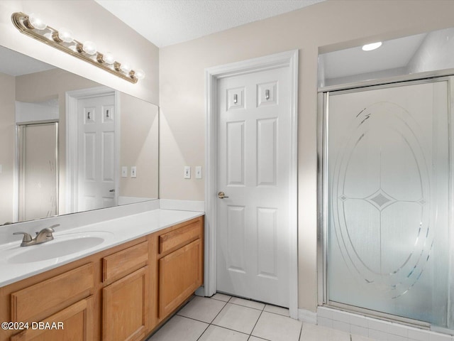 full bath with vanity, tile patterned floors, a stall shower, and a textured ceiling