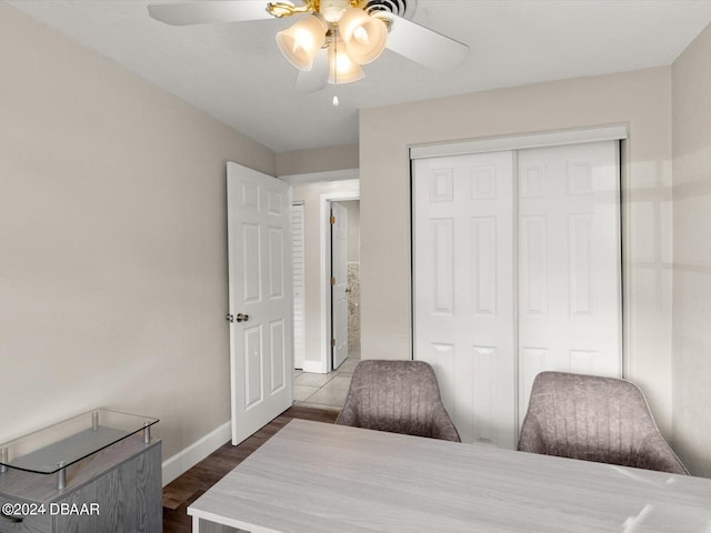 bedroom with a closet, baseboards, dark wood-type flooring, and ceiling fan