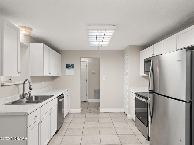 kitchen with visible vents, a sink, white cabinetry, stainless steel appliances, and light tile patterned floors