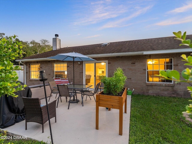 back of property featuring brick siding, a chimney, outdoor dining area, and a patio