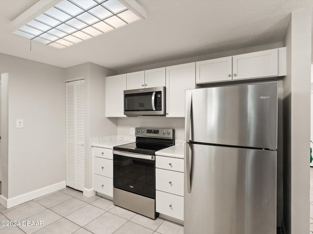 kitchen featuring white cabinetry, stainless steel appliances, light countertops, and baseboards