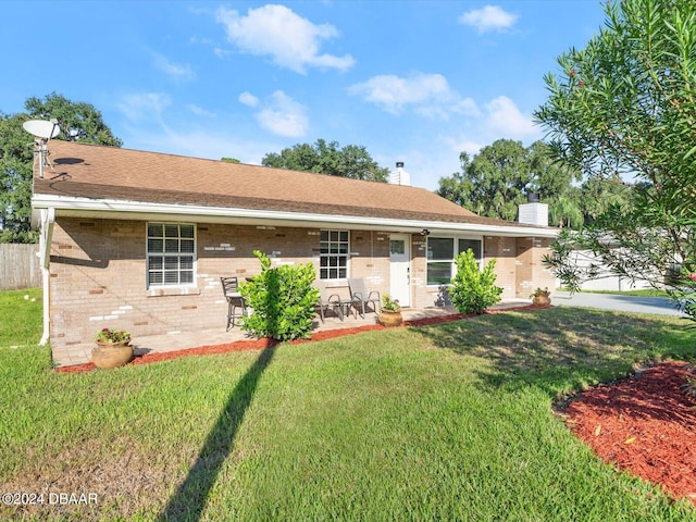 single story home featuring fence, a chimney, a front lawn, a patio area, and brick siding