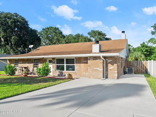 ranch-style home with a front lawn, a gate, cooling unit, brick siding, and a chimney