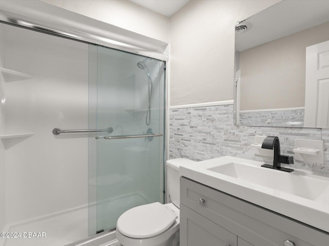 bathroom featuring toilet, tile walls, wainscoting, a shower stall, and vanity