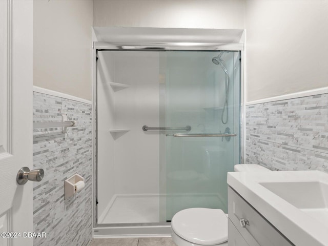 full bathroom featuring a wainscoted wall, a shower stall, tile walls, and toilet