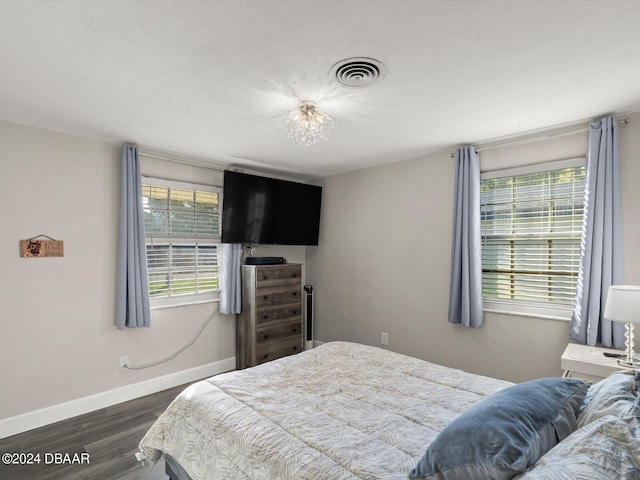 bedroom with wood finished floors, multiple windows, baseboards, and visible vents