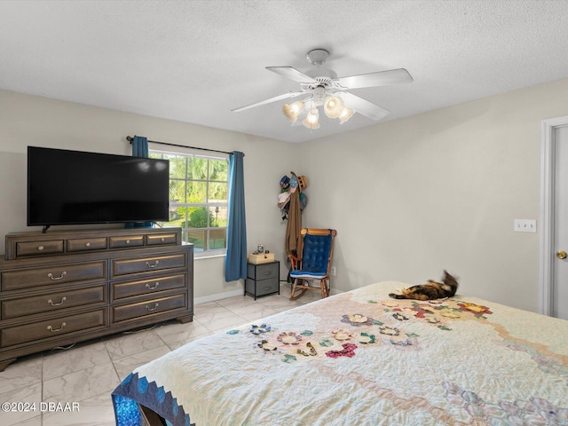 bedroom featuring ceiling fan, marble finish floor, and a textured ceiling