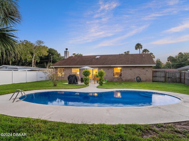 view of swimming pool featuring a lawn, area for grilling, a fenced backyard, a fenced in pool, and a patio area