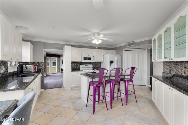 kitchen with white cabinets, white appliances, sink, and a center island