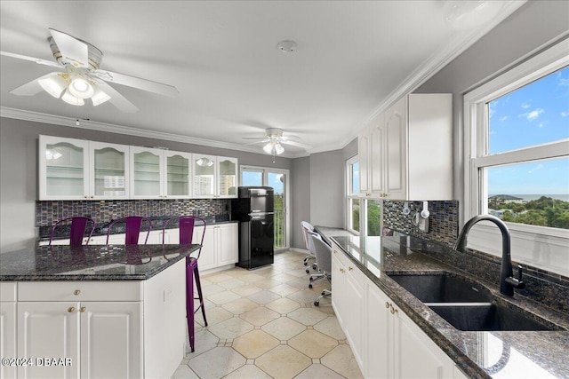 kitchen with black refrigerator, white cabinets, decorative backsplash, sink, and dark stone countertops