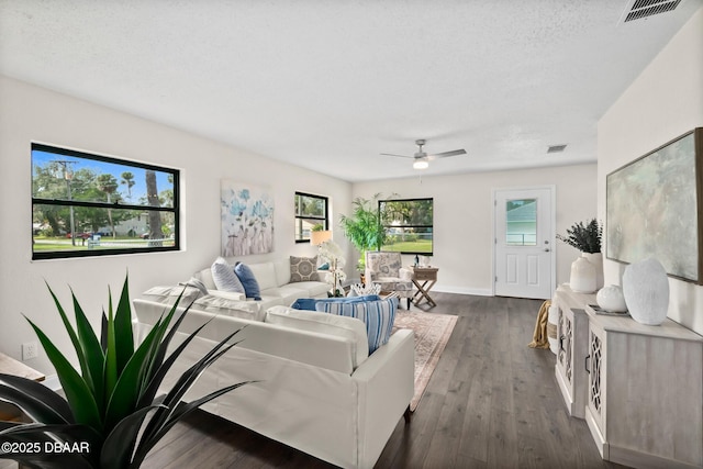 living room with visible vents, ceiling fan, and dark wood-style flooring