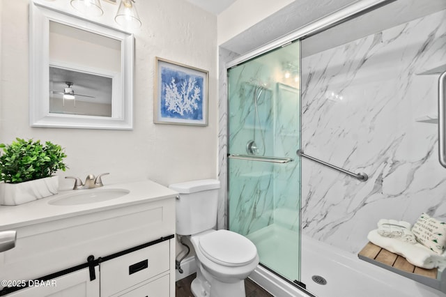 bathroom with toilet, a marble finish shower, a ceiling fan, and vanity