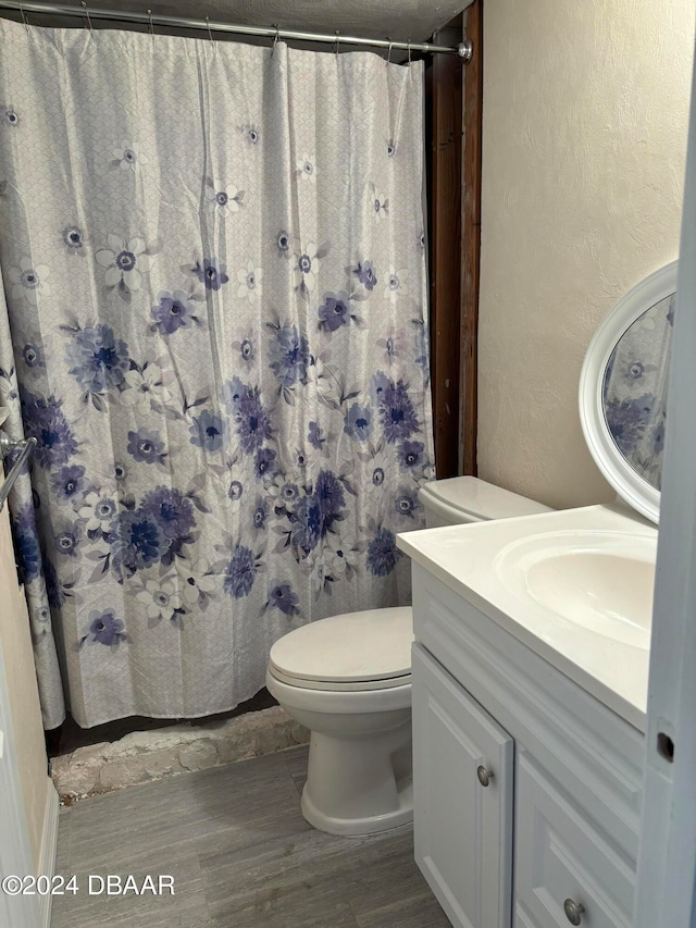 bathroom with toilet, vanity, wood-type flooring, and walk in shower