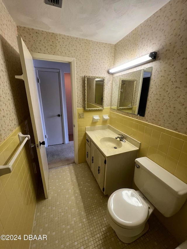 bathroom with tile walls, tile patterned floors, vanity, a textured ceiling, and toilet