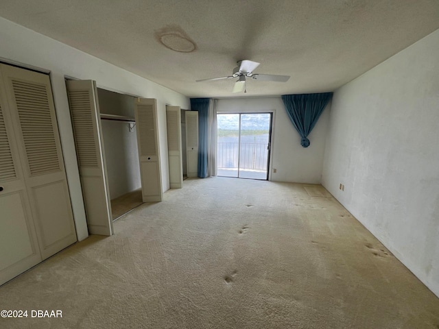 unfurnished bedroom with ceiling fan, access to exterior, two closets, and light colored carpet