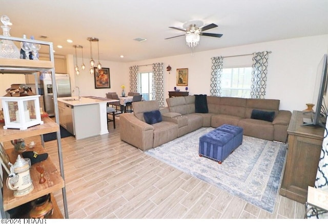 living room featuring sink, ceiling fan, and light hardwood / wood-style flooring