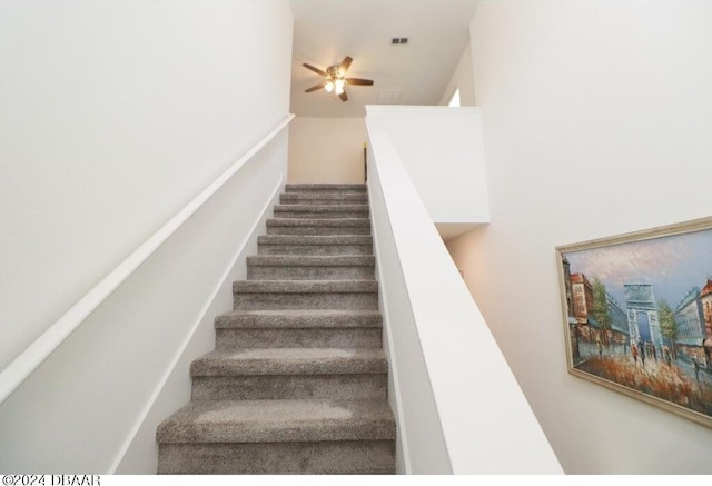 stairs featuring ceiling fan