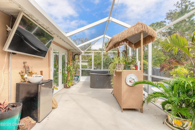 view of patio featuring a hot tub and glass enclosure