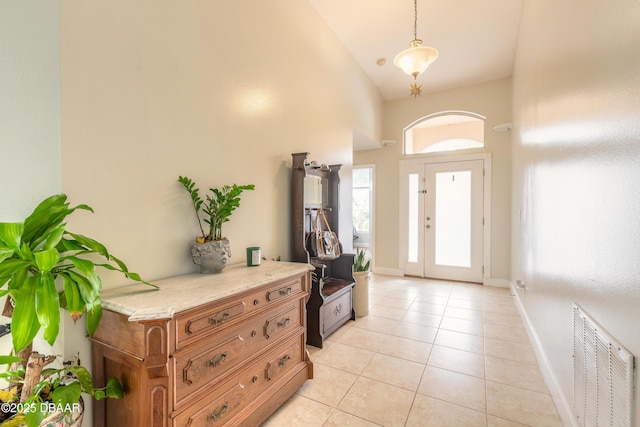 foyer with light tile patterned flooring and high vaulted ceiling