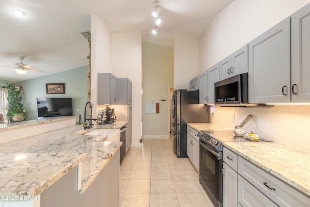 kitchen with stainless steel appliances, lofted ceiling, light tile patterned floors, and light stone counters