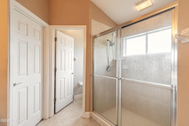 bathroom featuring lofted ceiling, tile patterned floors, and a shower with door