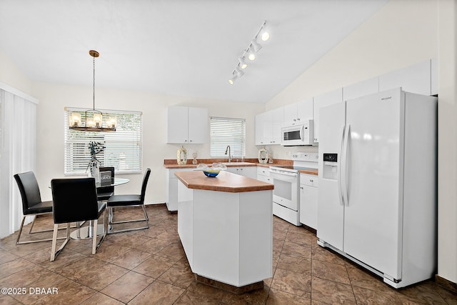 kitchen with white appliances, white cabinets, a sink, vaulted ceiling, and a center island