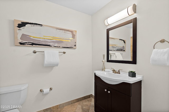 bathroom with baseboards, toilet, and vanity