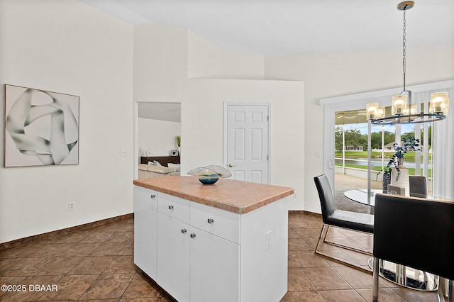 kitchen with a chandelier, a kitchen island, light countertops, white cabinetry, and hanging light fixtures