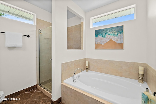 full bathroom featuring a stall shower, a garden tub, plenty of natural light, and baseboards