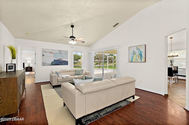 living area featuring dark wood-style flooring, ceiling fan, baseboards, a chandelier, and high vaulted ceiling