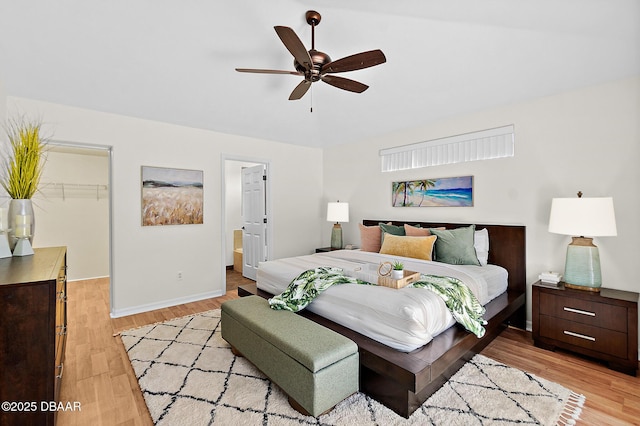 bedroom with a spacious closet, light wood finished floors, baseboards, connected bathroom, and a closet