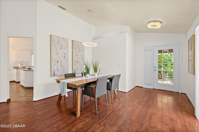 dining room with lofted ceiling, wood finished floors, and baseboards