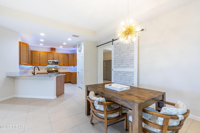 dining space featuring light tile patterned floors, a barn door, an inviting chandelier, and sink