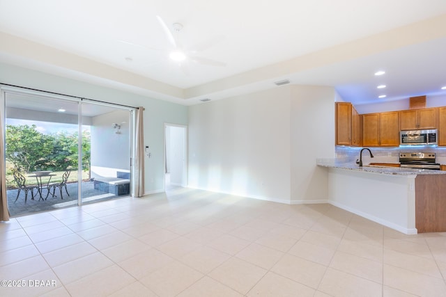 kitchen with light stone countertops, appliances with stainless steel finishes, ceiling fan, sink, and light tile patterned floors