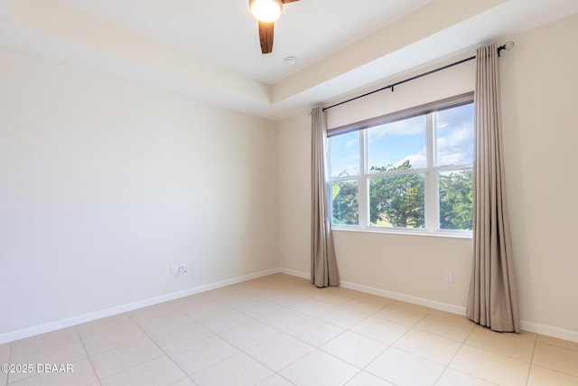 tiled spare room with a raised ceiling and ceiling fan