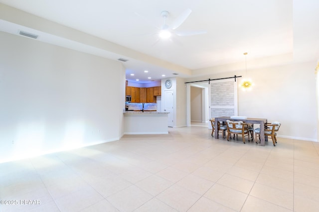 dining room featuring ceiling fan, a barn door, and light tile patterned floors