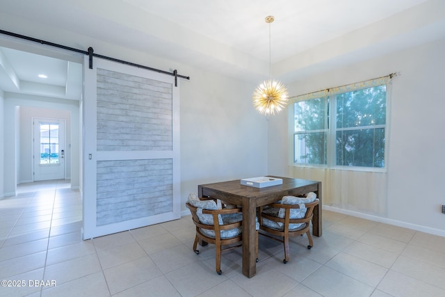 dining area featuring light tile patterned floors, a barn door, and a tray ceiling