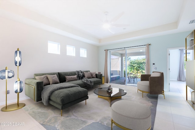 living room featuring ceiling fan, light tile patterned flooring, and a raised ceiling