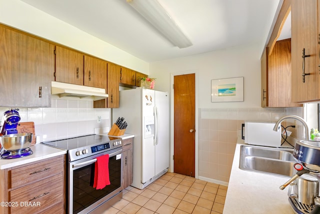2530 Nordman Ave, New Smyrna Beach, FL 32168 - kitchen with stainless steel electric stove, under cabinet range hood, white fridge with ice dispenser, a sink, and light countertops