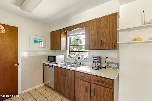 2530 Nordman Ave, New Smyrna Beach, FL 32168 - kitchen with stainless steel dishwasher, a sink, light countertops, brown cabinets, and tile walls