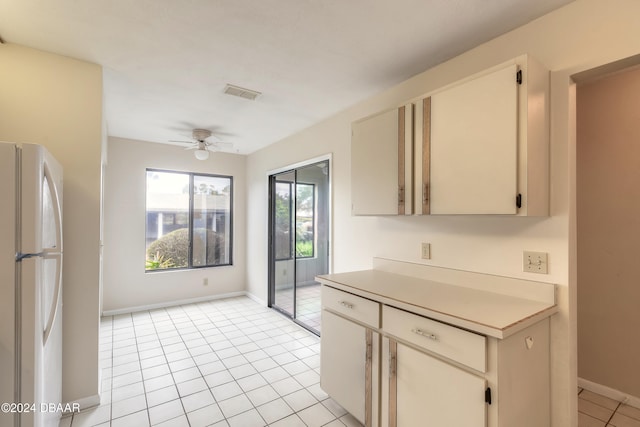 kitchen featuring cream cabinets, white refrigerator, ceiling fan, and light tile patterned flooring