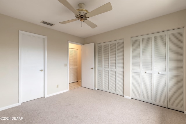 unfurnished bedroom with light carpet, ceiling fan, and multiple closets