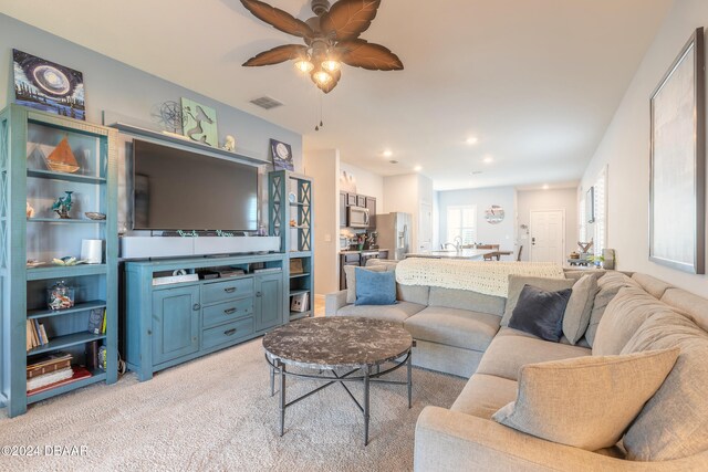 living room featuring light colored carpet and ceiling fan