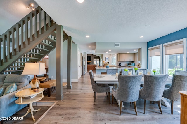 dining room featuring light wood-type flooring and a textured ceiling